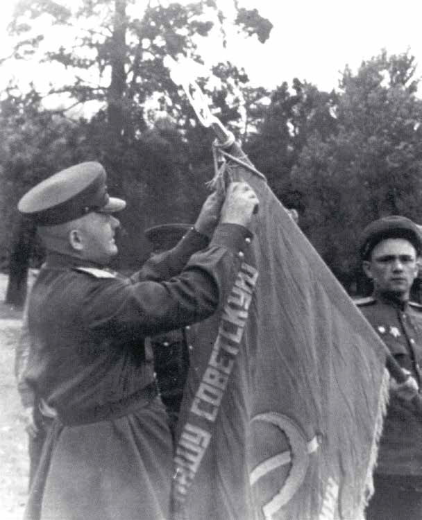 Командир 11-й ОБрПС В.Г. Ступаченко прикрепляет орден Богдана Хмельницкого III степени к Боевому знамени 248-го ОБПС. Июнь 1945 г.